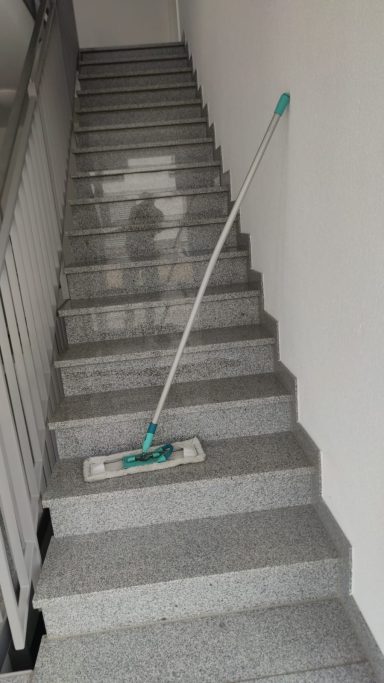 Bodenwischer steht auf einer grauen Treppe mit weißen Wänden.